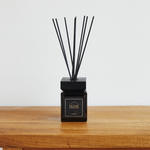 
                    
                      Difusor de aromas cubo negro con varillas sobre mesa de madera-
                    
                  