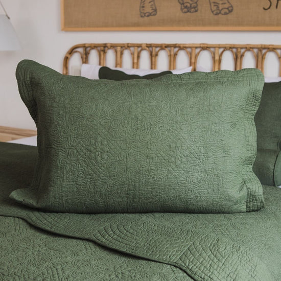 Funda de almohada verde con patrón quilted tradicional sobre cama-verde