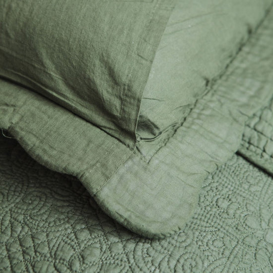 Funda de almohada verde texturizada estilo tradicional sobre superficie acolchada-verde