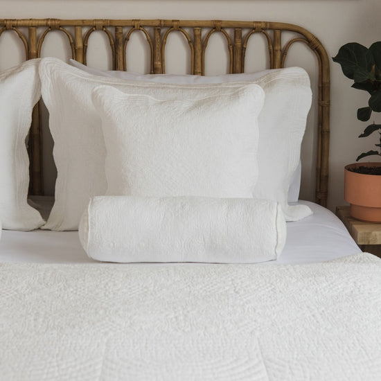 Funda de almohón blanca con textura en cama con cabecero de bambú-natural