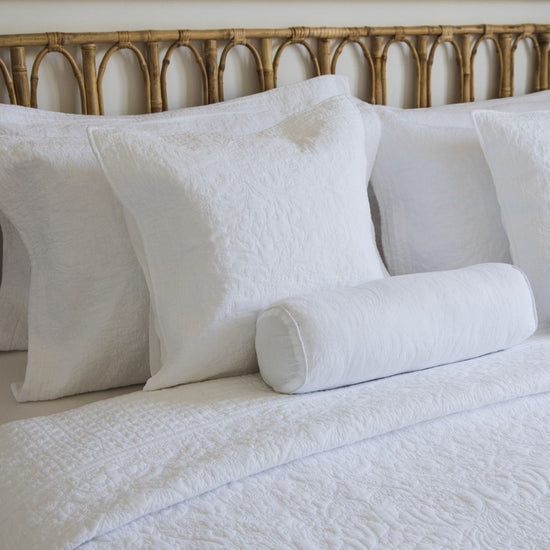 Almohada blanca decorativa con funda Calabria en cama con cabecero bambú-blanco