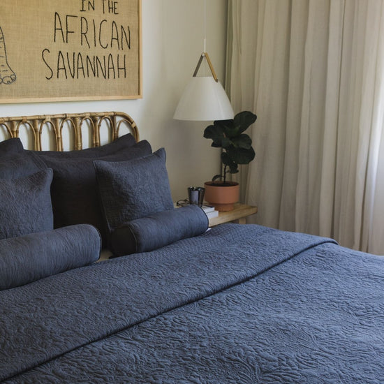 Cama con cubrecama gris azulado, almohadas a juego y decoración minimalista-gris