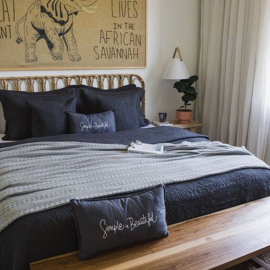 Cama con cubrecama gris, almohadas azul marino y arte de elefante-gris
