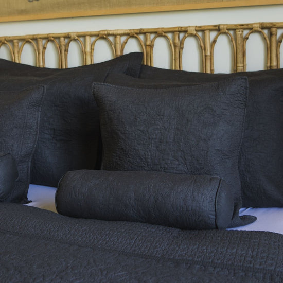 Almohadas decorativas gris oscuro sobre cama con cabecera dorada-gris