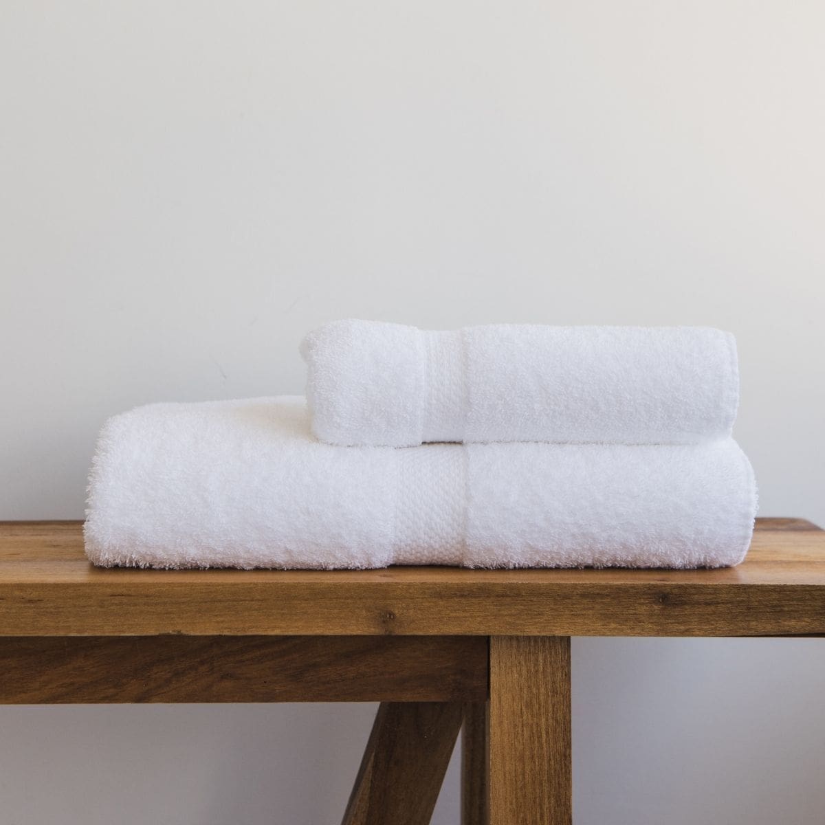 Juego de toalla y toallón blanco XL apilados sobre mesa de madera-blanco