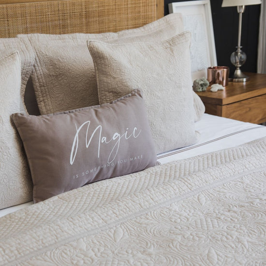 Almohada beige con texto "Magic is something you make" en cama-beige