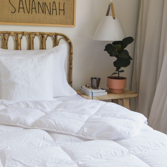 Cama con edredón blanco sintético, almohada y lámpara en dormitorio-blanco