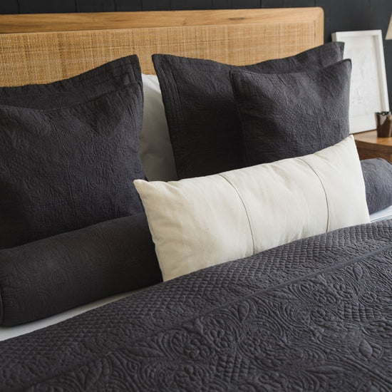 Almohada gris Amalfi decorativa en cama con headboard de ratán natural-gris