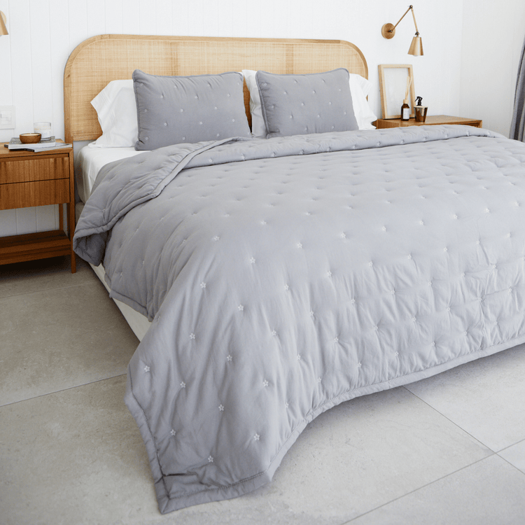Cubrecama gris con patrón punteado en cama de madera y rattan-gris