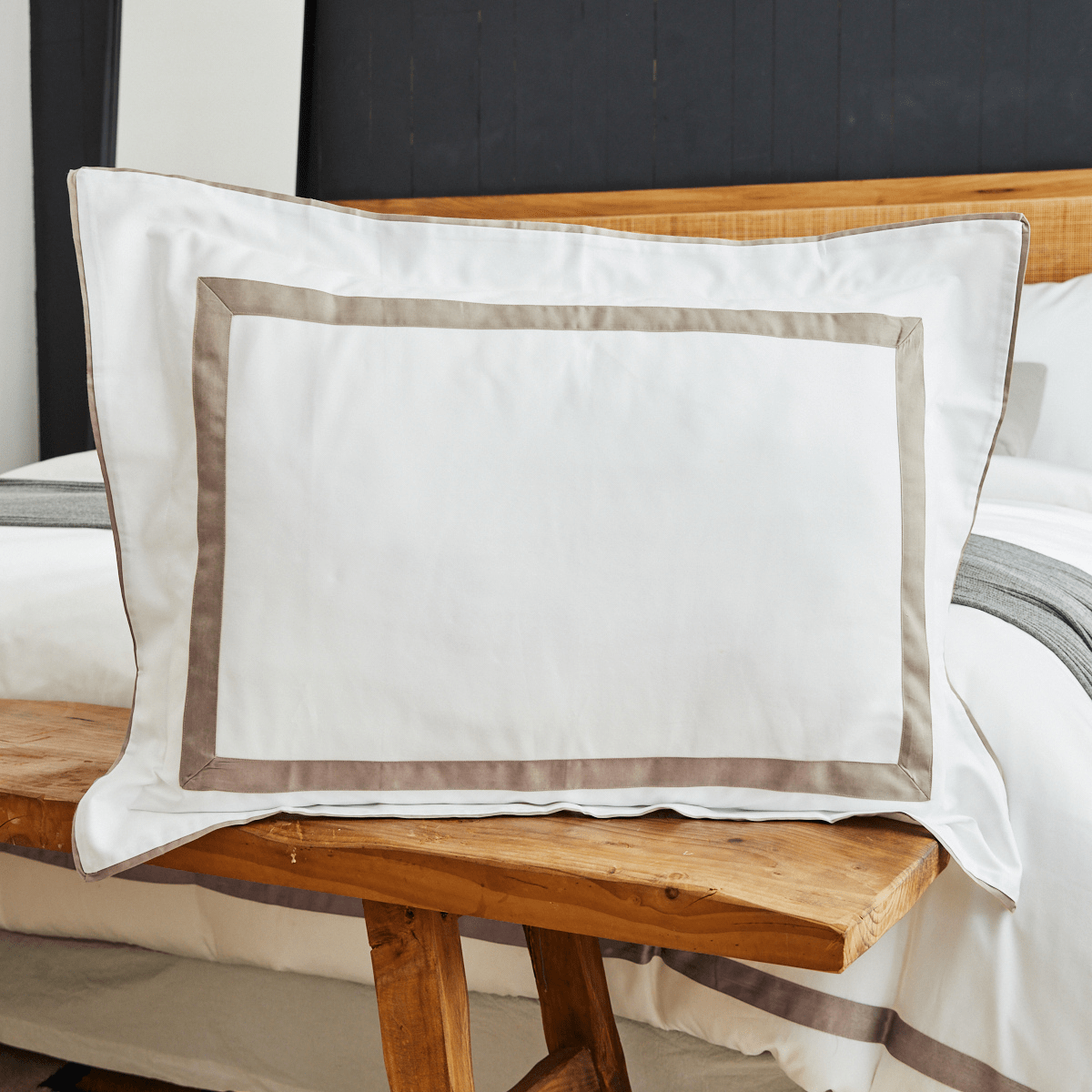 Almohada blanca con aplique beige sobre cama de madera-beige