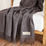 
                    
                      Manta de lana gris oscuro con flecos sobre cama de madera-gris
                    
                  