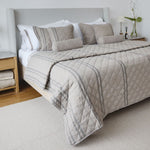
                    
                      Cubrecama beige con patrón de rayas y acolchado en cama moderna-
                    
                  
