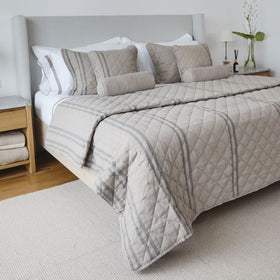 Cubrecama beige con patrón de rayas y acolchado en cama moderna-