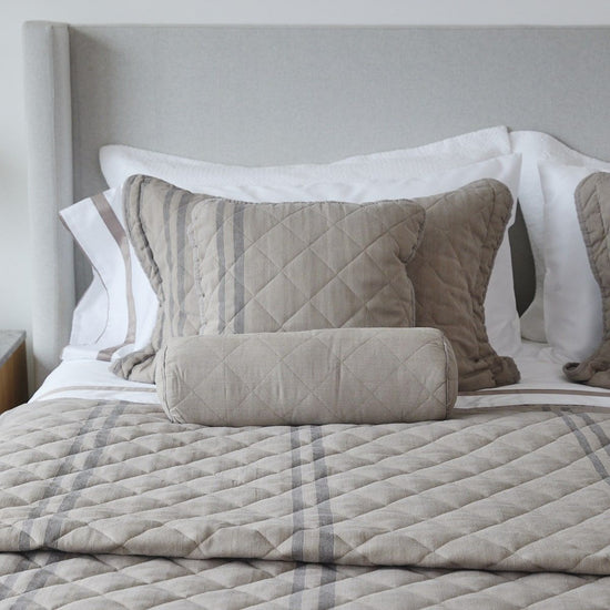 Almohadas decorativas beige con funda acolchada en cama-