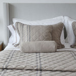 
                    
                      Cama con cubrecama acolchado beige, almohadas y cilindro decorativo-
                    
                  