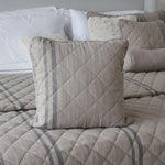 
                    
                      Almohada beige acolchada con patrón de diamantes sobre cama-
                    
                  
