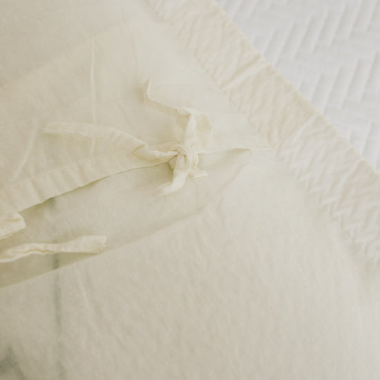 Funda de almohada blanca con textura tejida y detalle de nudo-natural