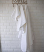 
                    
                      Toallas blancas colgadas en perchero de baño con letrero TOWELS-blanco
                    
                  