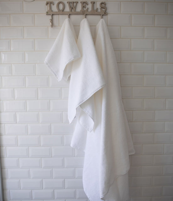 Toallas blancas colgadas en perchero de baño con letrero TOWELS-blanco