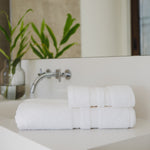 
                    
                      Set de toallas blancas dobladas en baño minimalista con espejo-blanco
                    
                  