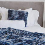 
                    
                      Cama con manta azul texturizada, almohadas blancas y cabecero gris-azul
                    
                  