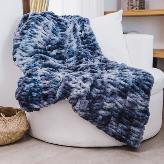 Manta azul texturizada tipo piel draped sobre sillón blanco moderno-azul