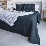 
                    
                      Cubrecama azul oscuro con almohadas decorativas en cama gris-azul
                    
                  