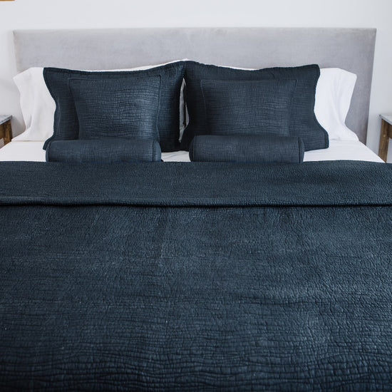 Funda de almohada azul oscuro con textura tradicional en cama-azul