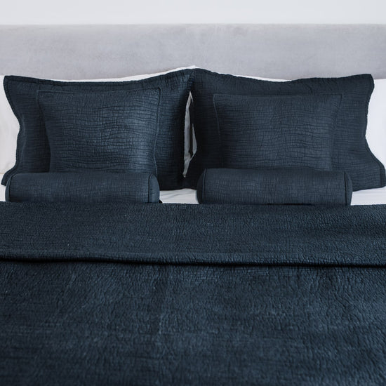 Cubrecama azul oscuro con almohadas decorativas en cama individual-azul
