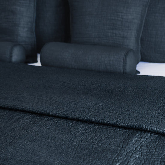 Cubrecama azul oscuro con cojines decorativos en cama-azul