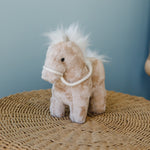 
                    
                      Peluche caballo beige con crin blanca y arnés sobre tapete tejido-marron
                    
                  