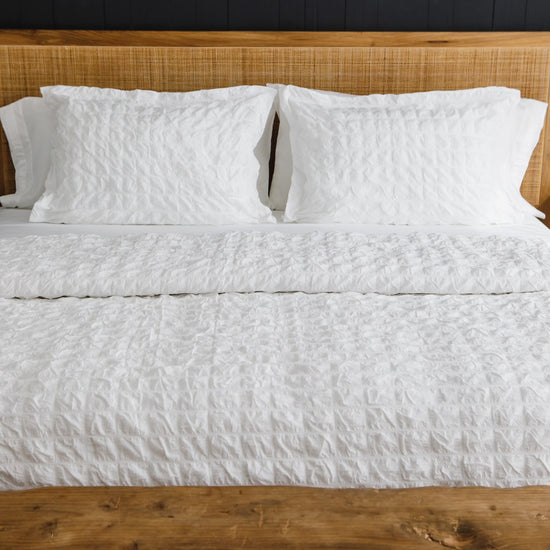 Cama con funda edredón waffle blanco y dos almohadas blancas-blanco