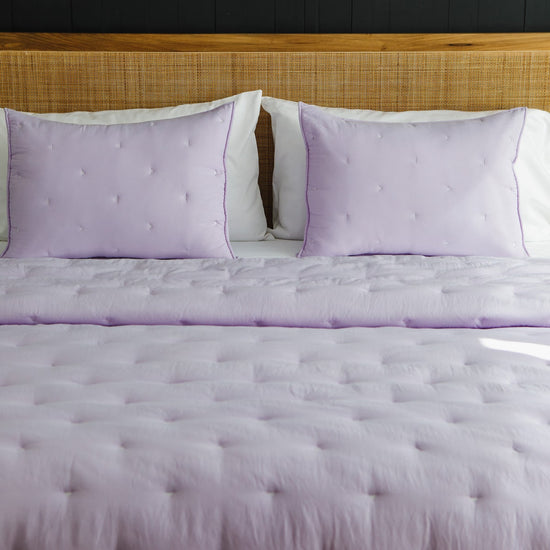 Cubrecama acolchado lila con almohadas a juego en cama moderna-lila