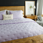 
                    
                      Cubrecama acolchado lila con almohadas a juego en cama de madera-lila
                    
                  