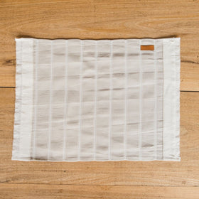 Individual de tela blanca con rayas grises sobre madera-rayado