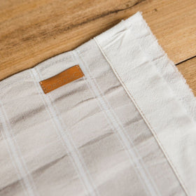 Paño blanco de lino con etiqueta marrón de cuero sobre madera-rayado