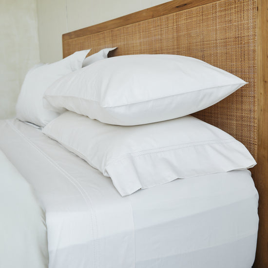 Funda de almohada blanca Venecia de hilo sobre cama con cabecero rattan-blanco