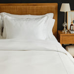 
                    
                      Cama con funda edredón blanco y almohadas en mesita noche madera-blanco
                    
                  
