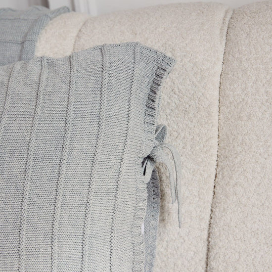 Detalle de funda de almohada gris con costuras y textura de tela-