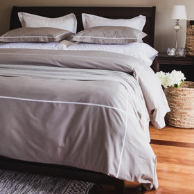 Cama con funda edredón gris, almohadas blancas y decoración elegante-gris