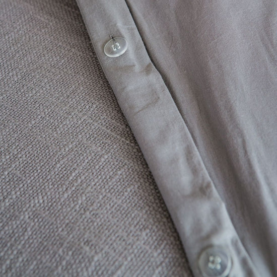 Detalle de botón transparente en funda de edredón gris claro-