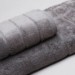 
                    
                      Set de toallas grises enrolladas mostrando texturas y tonos variados-gris oscuro
                    
                  