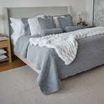 
                    
                      Cama con cubrecama gris acolchado y almohadas decorativas blancas-gris
                    
                  