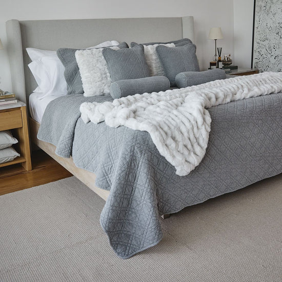 Cama con cubrecama gris acolchado y almohadas decorativas blancas-gris