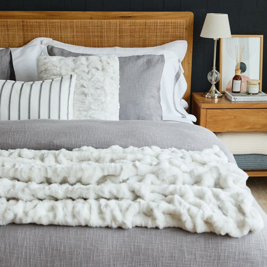 Cama moderna con edredón blanco texturizado y almohadas decorativas grises-