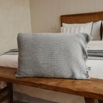 
                    
                      Funda de almohada gris texturizada sobre banco de madera en dormitorio-
                    
                  