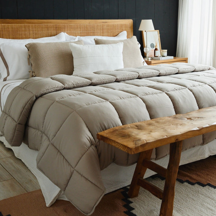 Edredón beige acolchado sobre cama con almohadas decorativas-beige