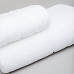 
                    
                      Set de cuatro toallas blancas enrolladas sobre superficie gris-blanco
                    
                  