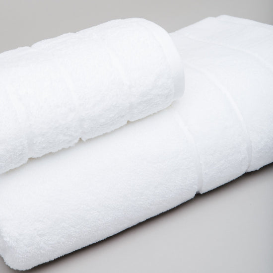 Set de cuatro toallas blancas enrolladas sobre superficie gris-blanco
