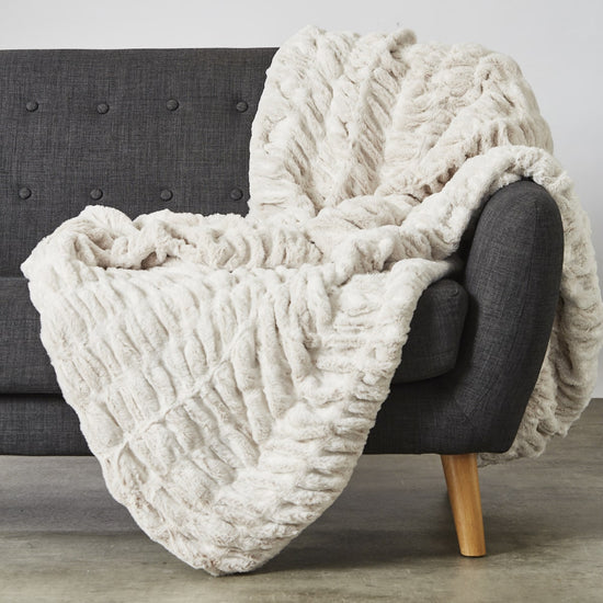 Manta blanca texturizada draped sobre silla gris con patas de madera-